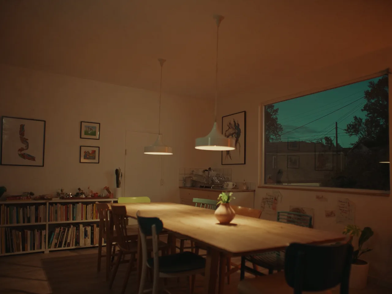 Salle commune avec grande table de bois et lampes chaudes